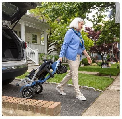 Woman Rolling Folded Scooter Away From Van