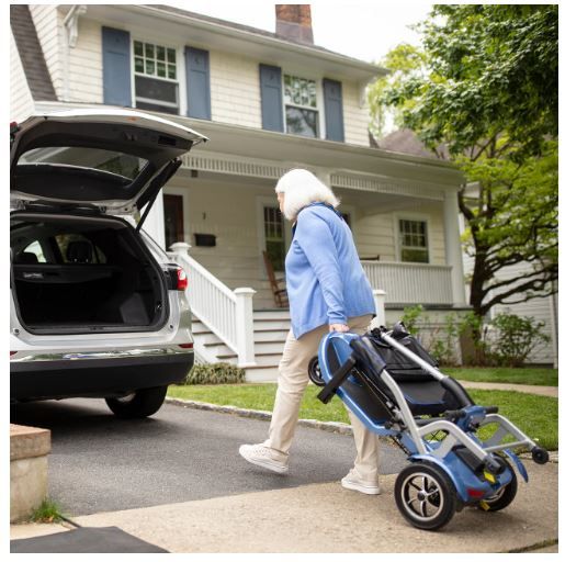 Woman Pulling Folded Scooter to Van With Open Trunk