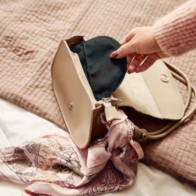 Woman placing SenSura Mio Click Black 2-Piece Ostomy Pouch in Purse
