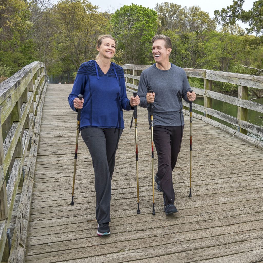 Couple walks on bridge together with Summit walking sticks
