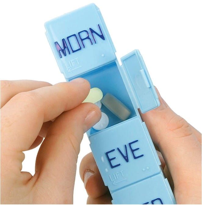 Hands placing medication into a pill organizer