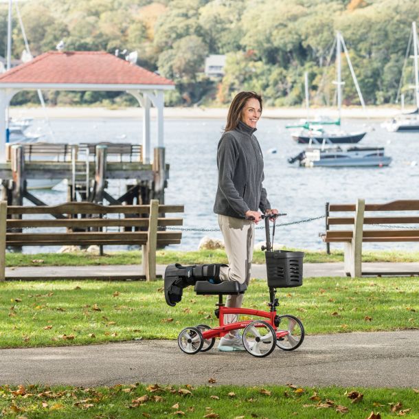 Woman using red knee walker in park 2