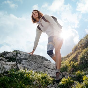 A hiker crosses rocky terrain wearing the knee brace.