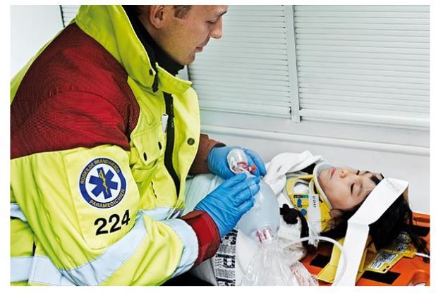 Child Lying on a Stretcher Wearing a Cervical Collar Besides a Paramedic