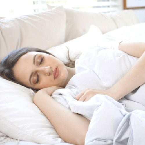 A woman sleeps with a COOLMAX weighted blanket