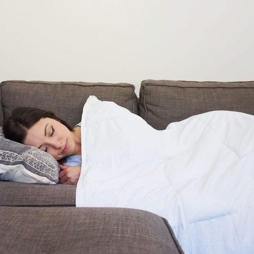 A woman naps on the couch with a COOLMAX Weighted Blanket.