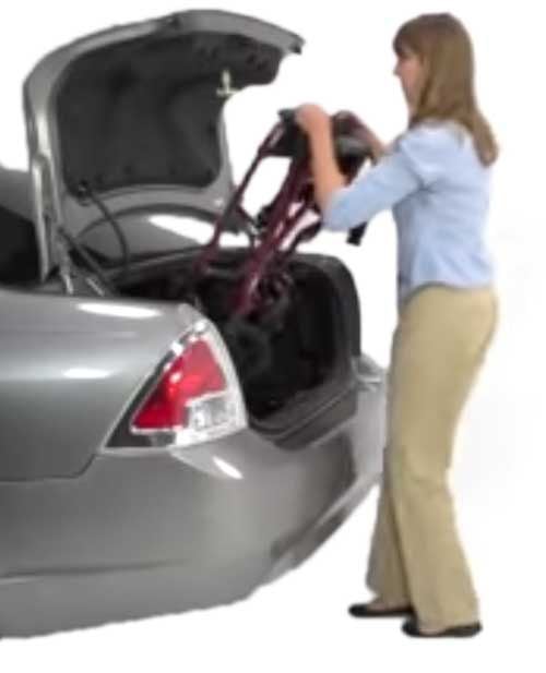 A woman puts the wheelchair in the trunk of the car
