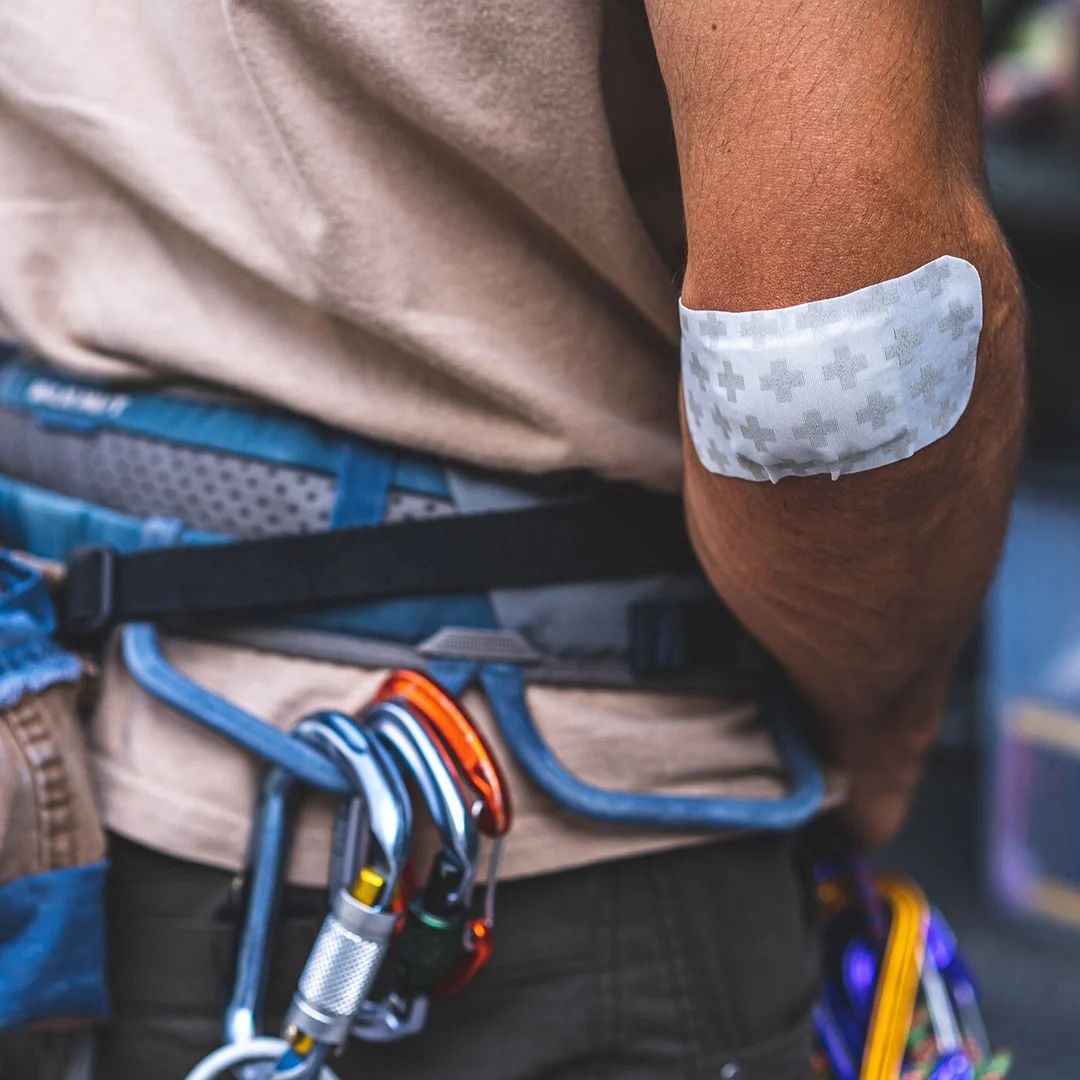 Man in rock climbing harness, with white bandage on elbow