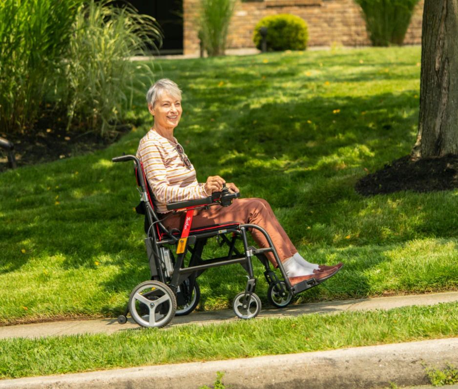 A user easily navigates the sidewalk in her Feather Power Folding Wheelchair