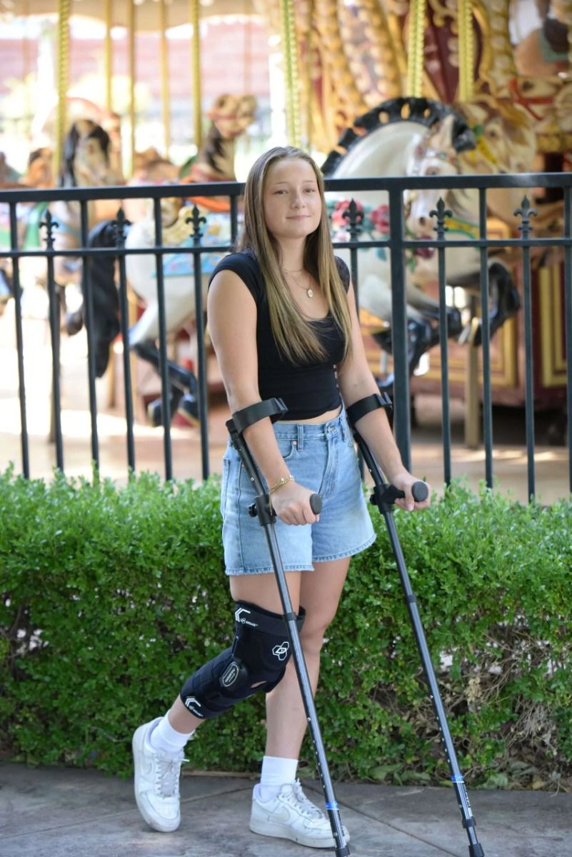 Woman walking by a carousel with forearm crutches