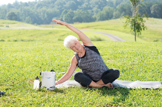 Woman uses the concentrator while doing yoga outdoors.