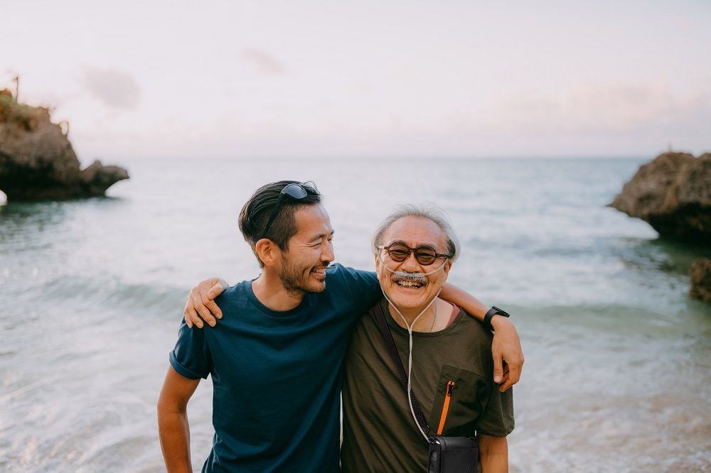 Lifestyle photo of son with dad who has the G5 inside carry bag at the ocean