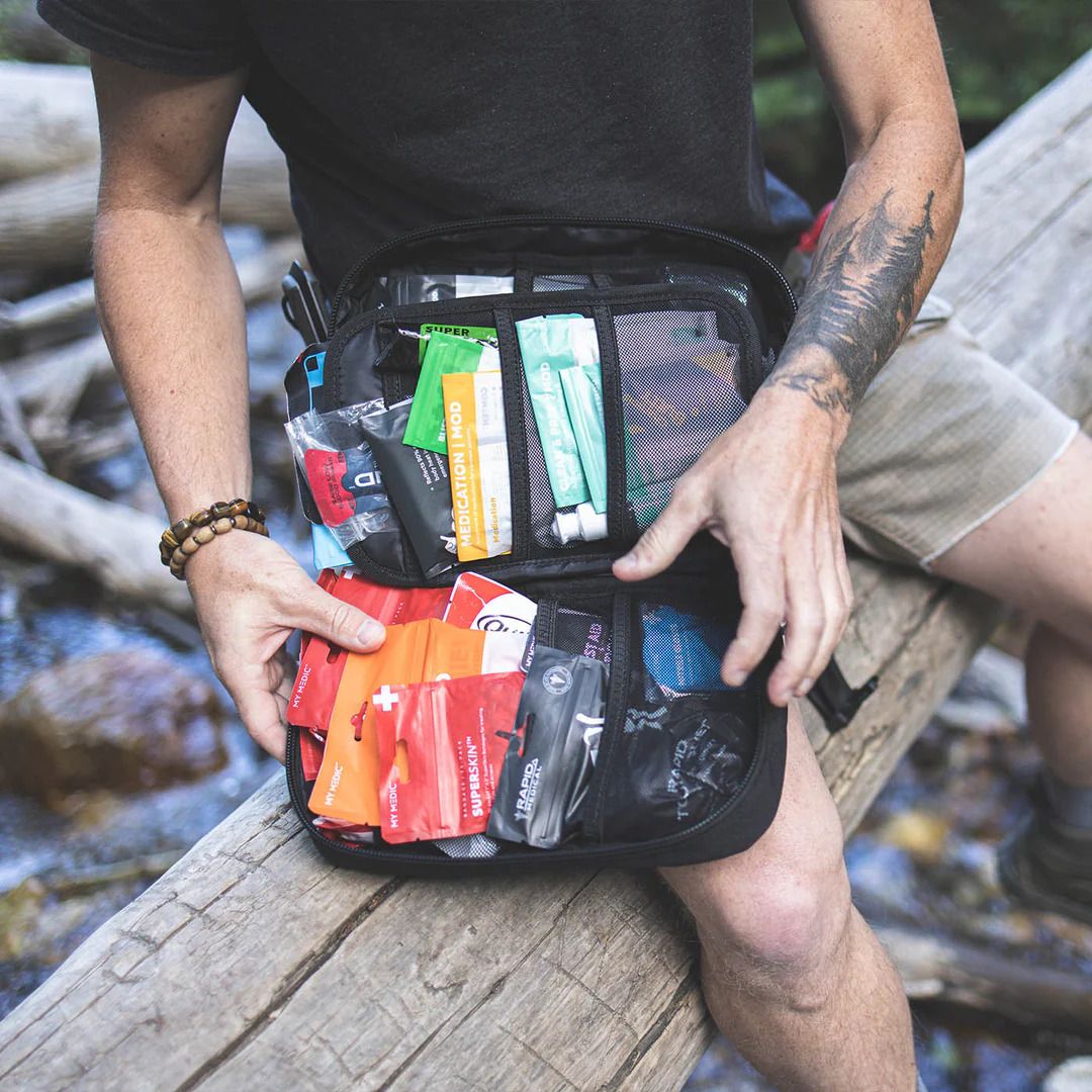 Man in the outdoors holding an open MyFAK kit