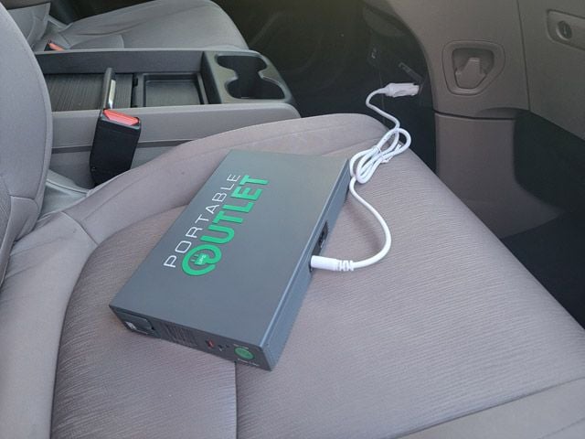 Portable outlet battery on car passenger seat, plugged into car outlet