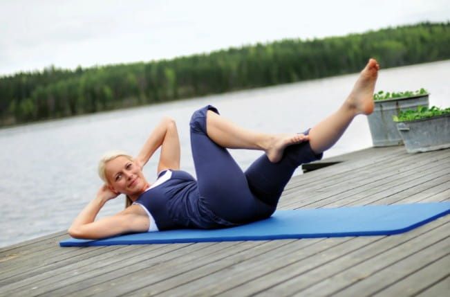 Side View of Woman Lying on Mat Doing Oblique Crunches
