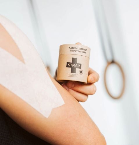 Someone applying the beige Strap Tape to their arm.