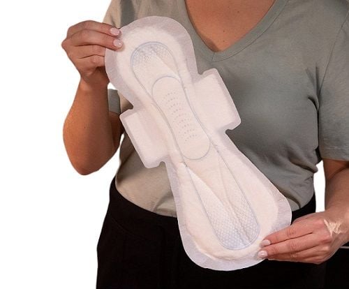 A person holding an unwrapped U by Kotex Overnight pad in front of them.