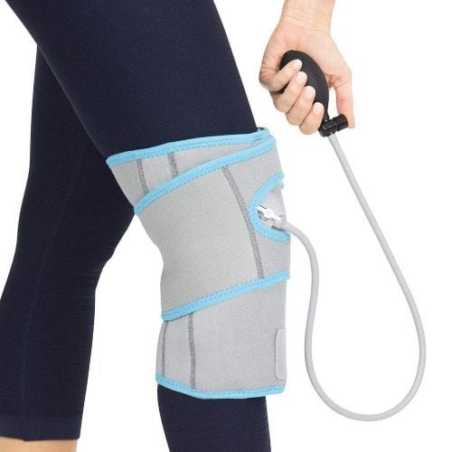 A user wears the knee wrap and adjusts the compression with the hand bulb