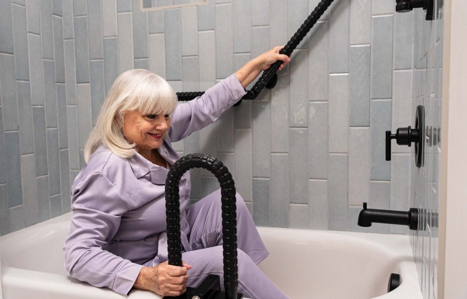 Woman in sitting position in bathtub using SafetyGrip for stability