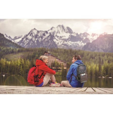 Lifestyle photo of a couple hiking and sitting on a boardwalk. The man has the Inogen G5 in a backpack. 