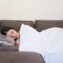 A woman naps on the couch with a COOLMAX Weighted Blanket.