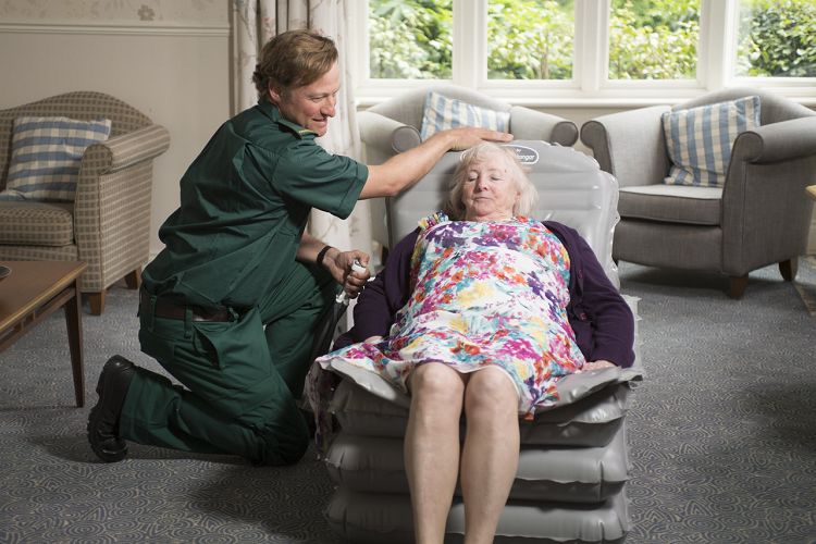 A man helps an elderly women up after she has fallen with the portable Mangar camel patient lift