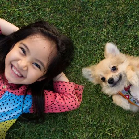 Smiling girl and her dog lie on the grass