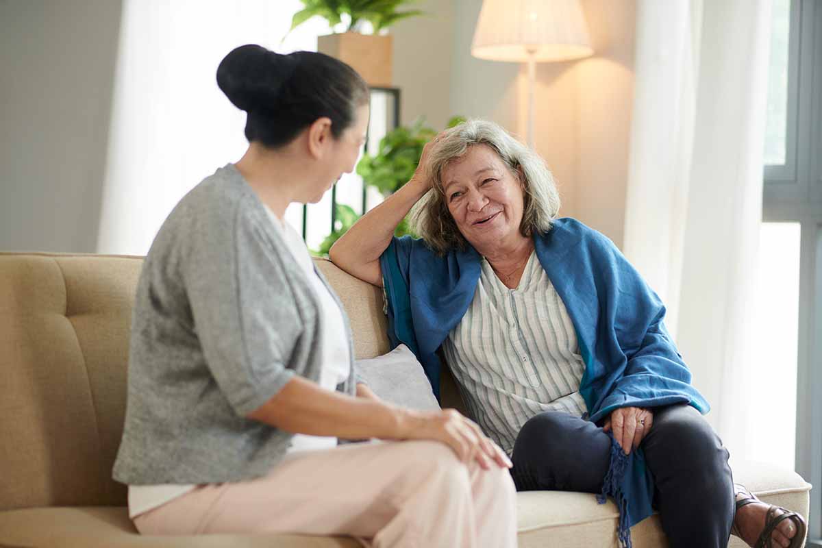 Older and younger woman chat on the couch