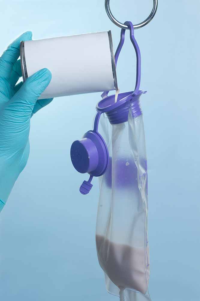 Gloved Hand Pouring Formula Into a Feeding Bag