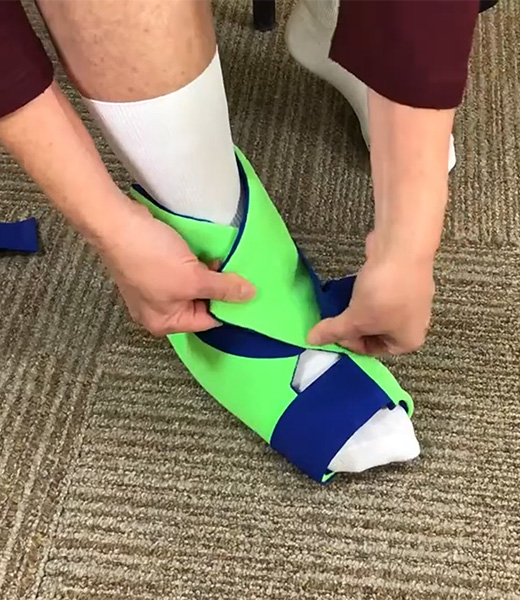 A user fastening the Polar Ice Foot/Ankle Wrap onto their foot.