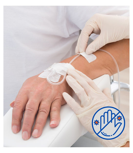 A medical worker attending to a patient's IV dressings.