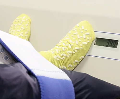 A patient's feet rest on the footboard with scale while weight is displayed.