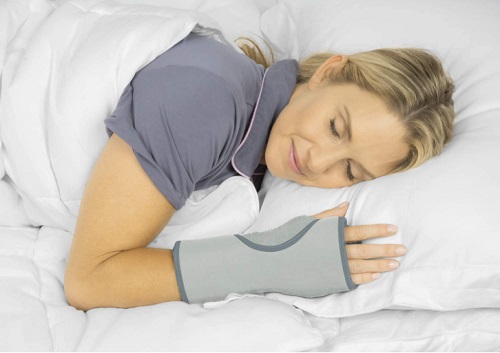 A woman sleeping while wearing the Vive Overnight Wrist Brace.